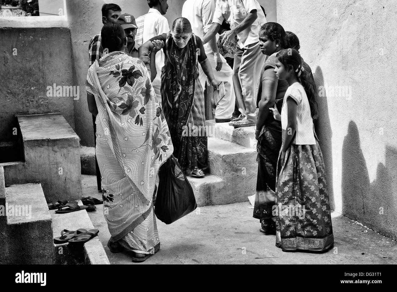 Vieille Femme indienne étant aidé en au Sri Sathya Sai Baba mobiles de proximité hôpital clinique. L'Andhra Pradesh, Inde. Noir et blanc. Banque D'Images