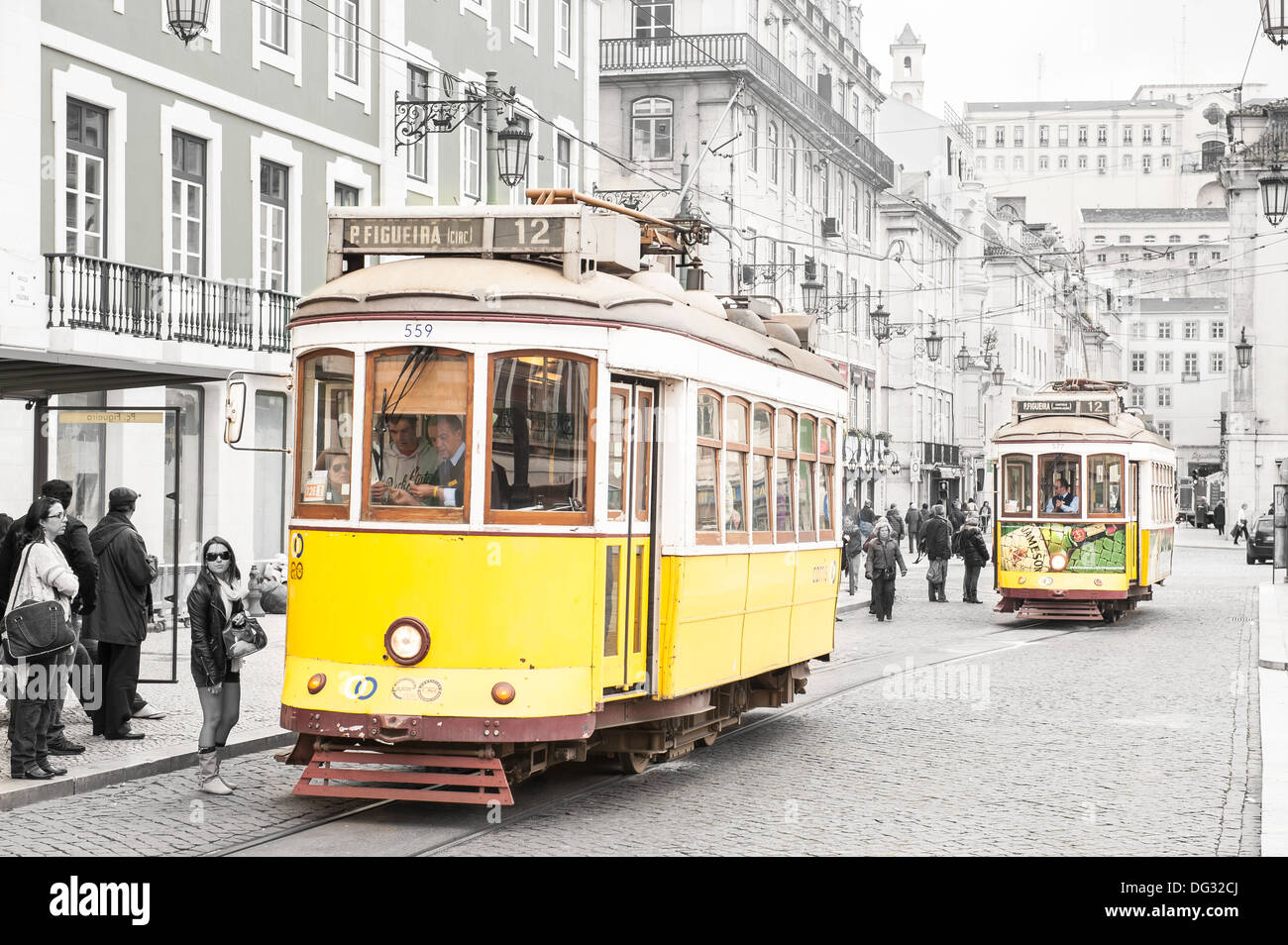 Les trams jaunes historique dans une rue pavée en place Figueira (AKA Praça da Figueira) dans la vieille ville de Lisbonne, Portugal Banque D'Images