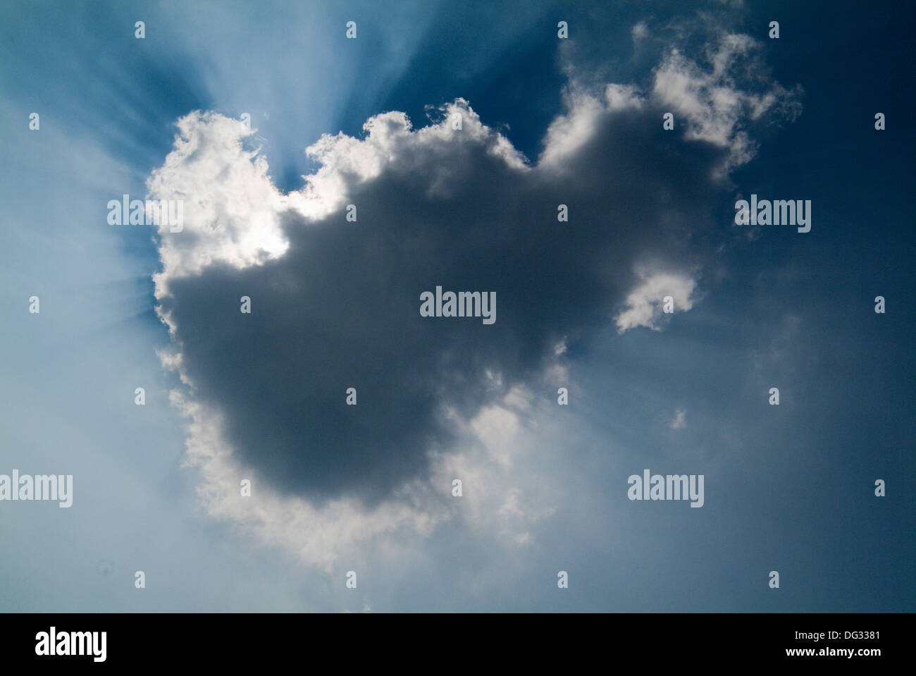 Seul nuage blanc dans un ciel d'été bleu avec soleil derrière Banque D'Images