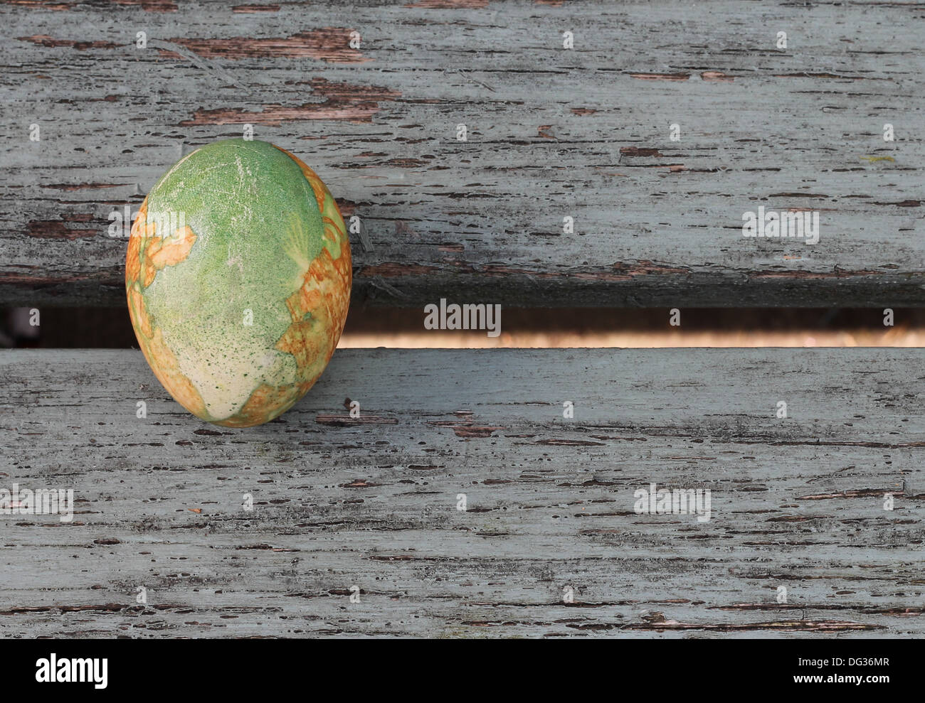 Un seul oeuf Peint, décoré dans le style grec traditionnel, marbré de vert et orange , assis sur de vieilles planches en bois peint, Banque D'Images