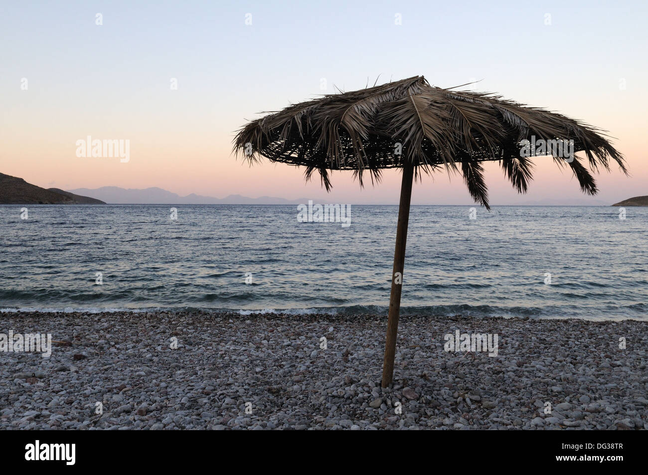 Parasol fabriqué à partir de feuilles sur plage de Livadia Tilos au crépuscule le Dodécanèse Grèce Banque D'Images