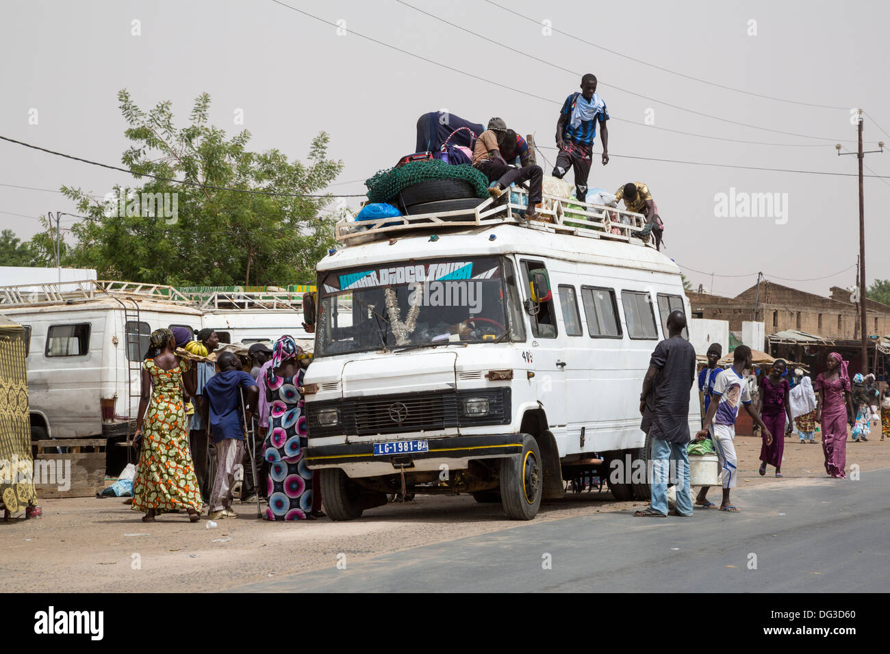 Sénégal, Touba. Transport local et la sécurité routière. Les jeunes hommes charger des marchandises sur top ; certains passagers vont monter. Banque D'Images