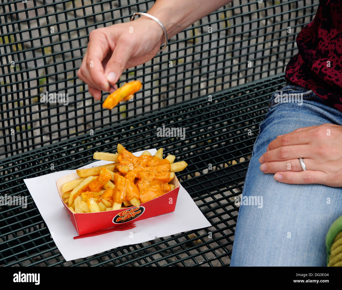 Manger des frites avec de la mayonnaise belge sur un siège public Banque D'Images