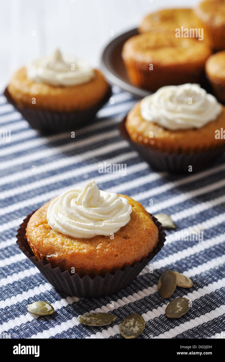 Muffins à la citrouille avec crème fouettée sur fond rayé bleu Banque D'Images