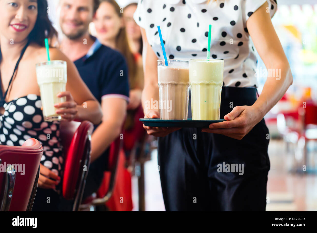Des amis ou des couples eating fast food et de boire des milk-shakes sur bar en restauration rapide américaine diner, la serveuse est prise des commandes Banque D'Images