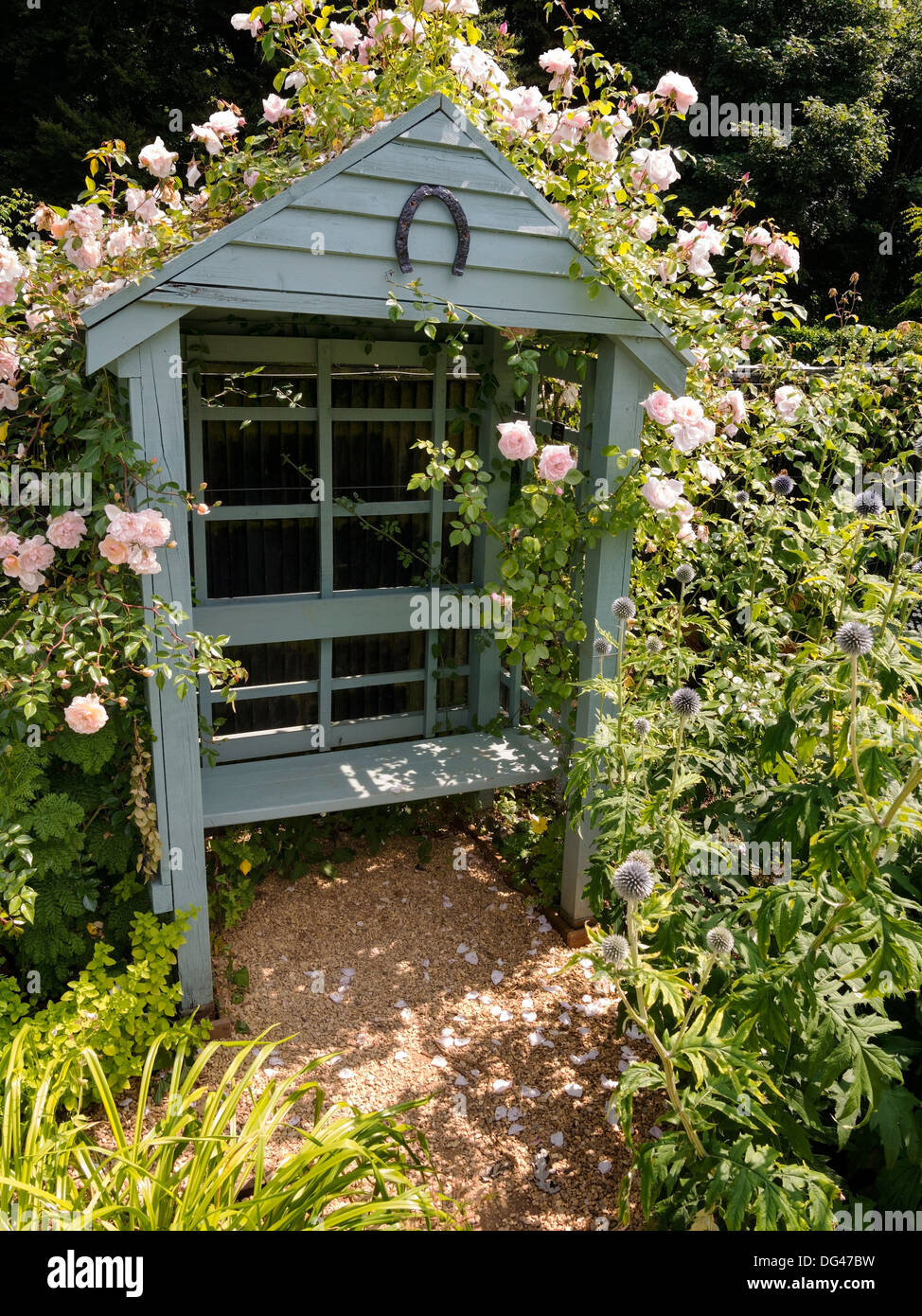 Jardin en bois orné arbor avec banquette et rosiers grimpants dans Chalet jardin, Jardins Barnsdale, Oakham, Rutland, England, UK Banque D'Images