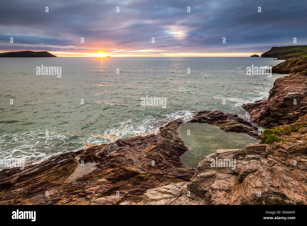 Vue du coucher de soleil sur la baie de Hayle avec les falaises rocheuses de Polzeath au premier plan et dans la distance Point pas-à-pas Banque D'Images