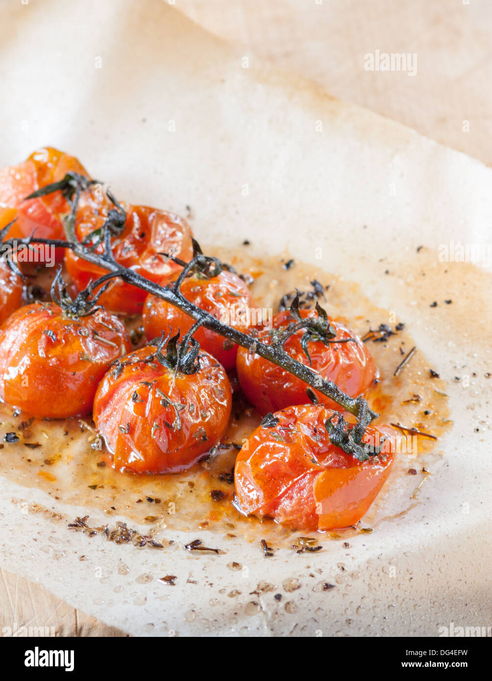 Tomates cerises grillées aux herbes sur du papier sulfurisé Banque D'Images