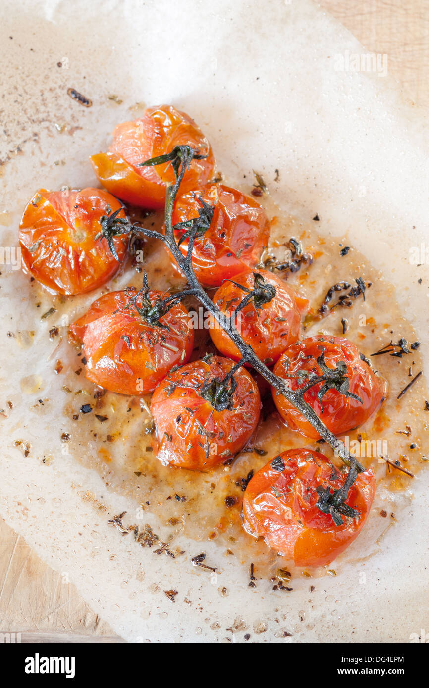 Tomates cerises grillées aux herbes sur du papier sulfurisé Banque D'Images