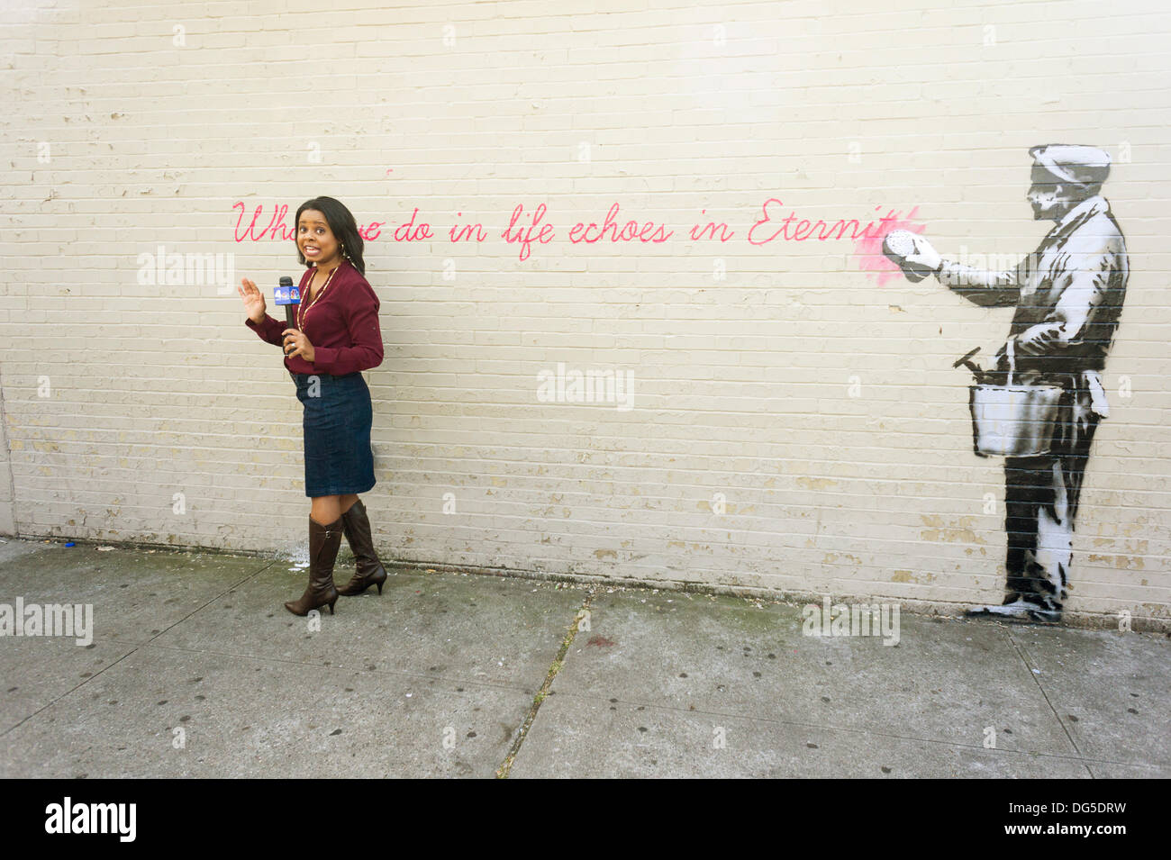 New York, USA. 14Th Oct, 2013. Un journaliste de NBC fait son stand-up dans le quartier de Woodside Queens à New York le lundi 14 octobre 2013, en face de la quatorzième tranche de l'art graffiti de Banksy, 'ce que nous faisons dans la vie résonne dans l'éternité". L'insaisissable artiste de rue, c'est la création d'œuvres autour de la ville chaque jour durant le mois d'octobre, accompagnée d'un message enregistré, vous pouvez entendre en appelant le numéro 1-800-656-4271 suivi de #  et le nombre d'œuvres. (© Richard B. Levine) Crédit : Richard Levine/Alamy Live News Banque D'Images