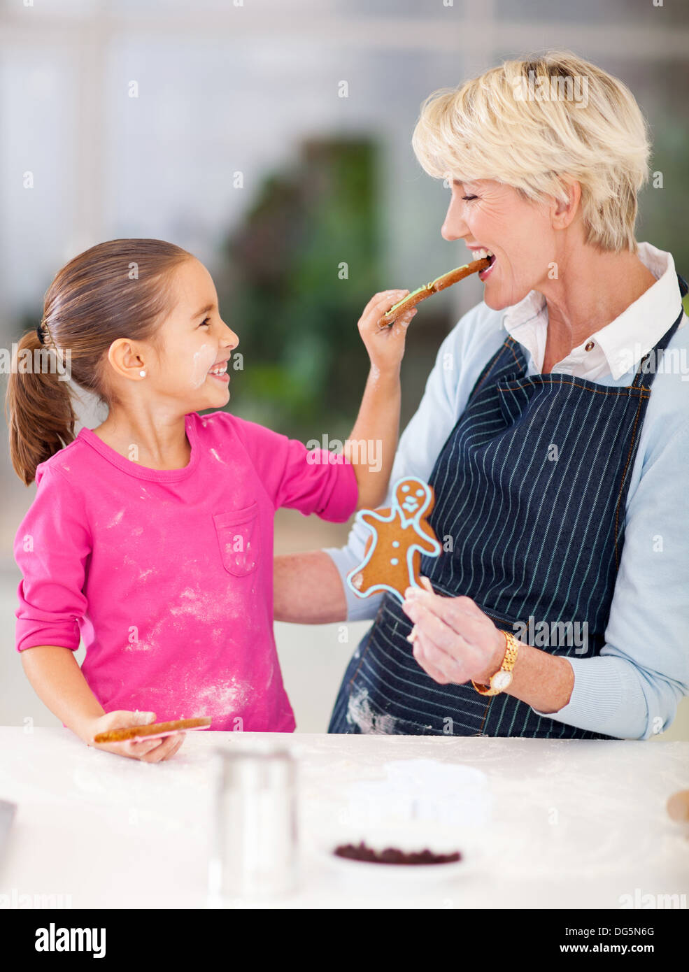 Cute little girl juste alimentation gingerbread cookies au four à sa grand-mère Banque D'Images