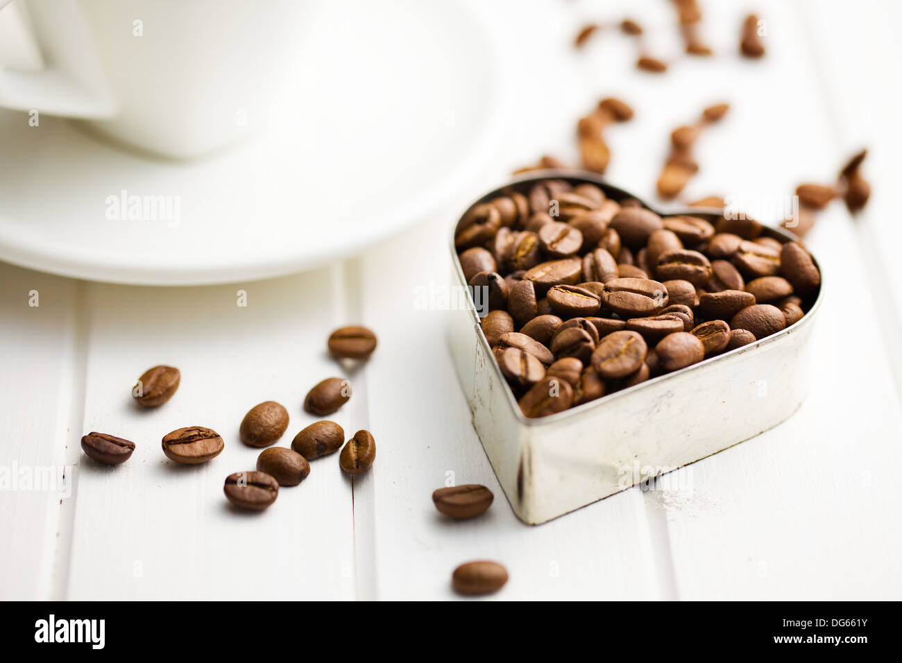 Café en grains en forme coeur sur table en bois blanc Banque D'Images
