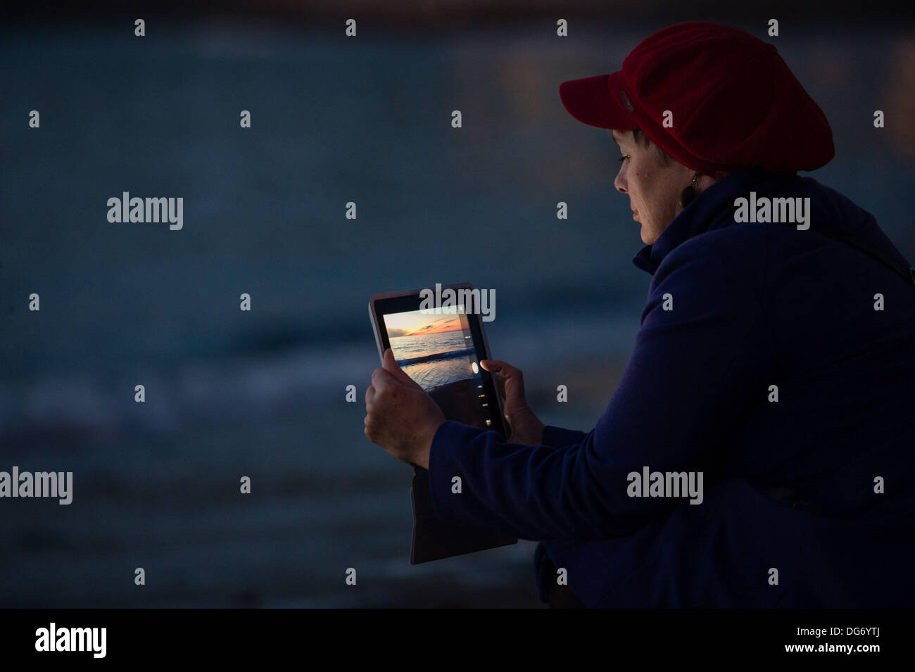 Pays de Galles Aberystwyth UK, 15 octobre 2013 une femme à l'aide de son ordinateur tablette pour photographier le ciel dramatique au crépuscule sur la baie de Cardigan, au large de la plage à Aberystwyth, Pays de Galles au Royaume-Uni. Après un accueil chaleureux et très sec journée ensoleillée dans l'ouest du pays de Galles , les prévisions pour les prochaines due est de plus en plus de nuages et averses de pluie Crédit photo : Keith morris/Alamy Live News Banque D'Images