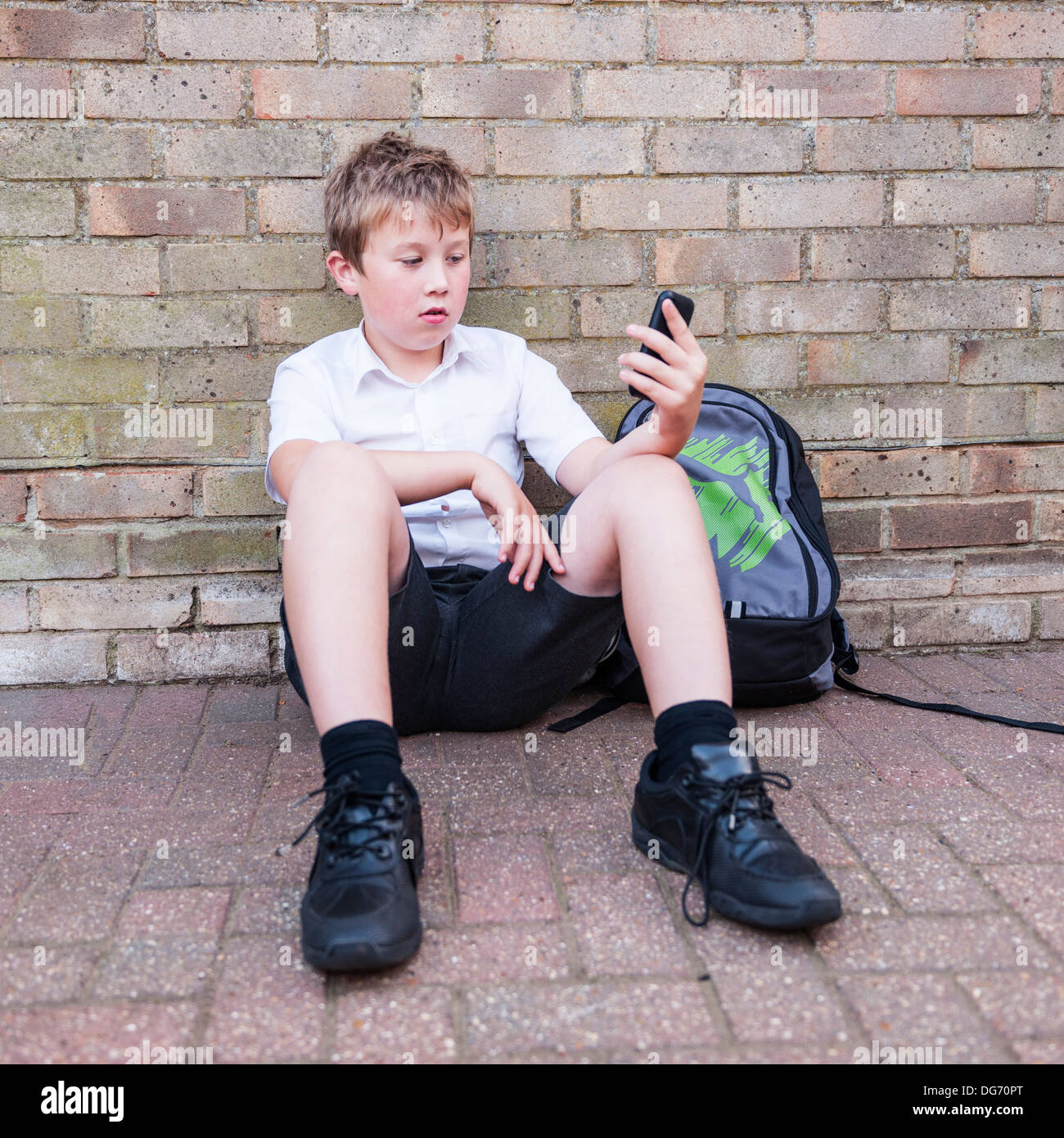 Un garçon de 10 à la triste comme il regarde son téléphone portable montrant les effets de l'intimidation par texte ou de réseau social au Royaume-Uni Banque D'Images