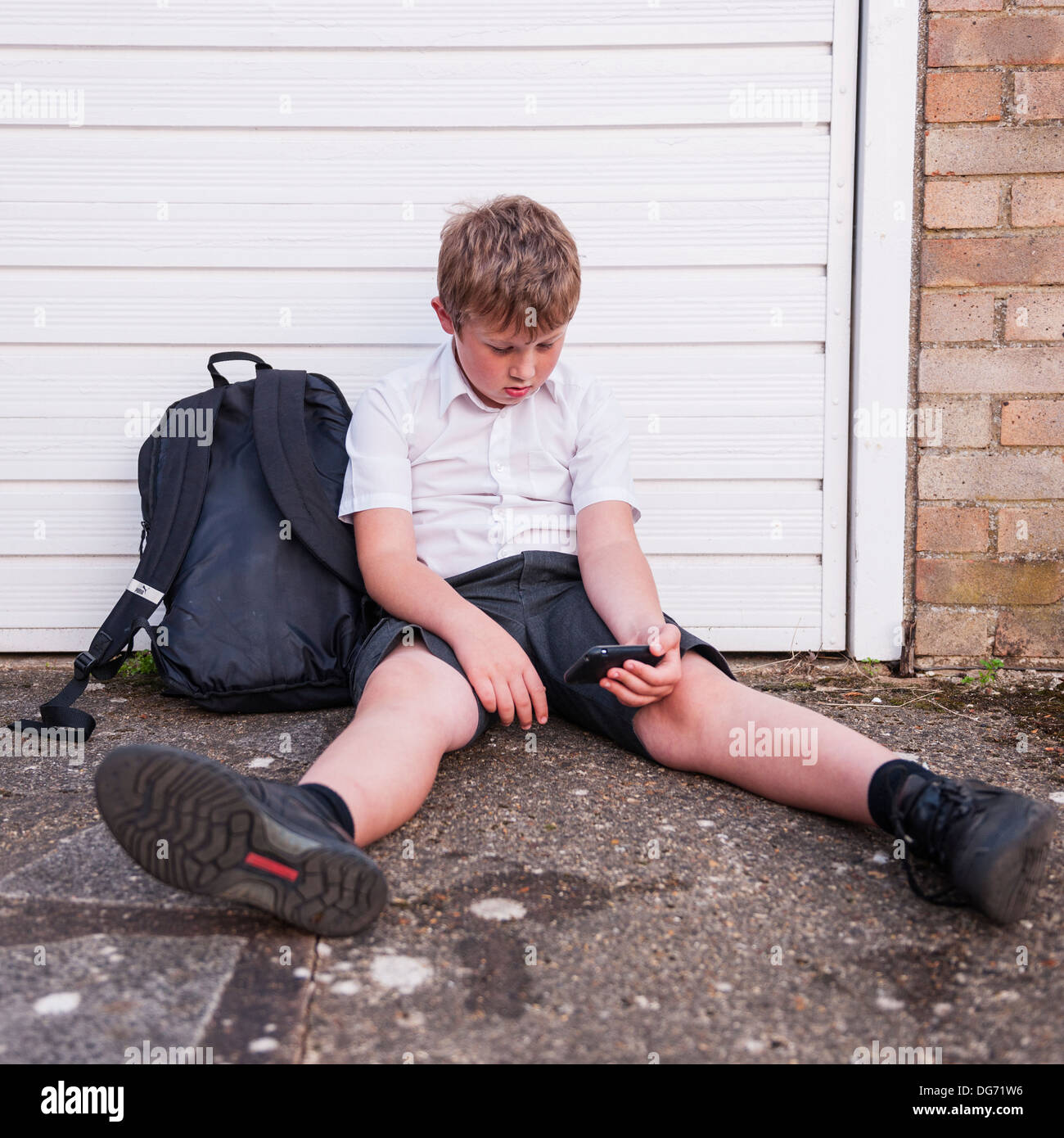 Un garçon de 10 à la triste comme il regarde son téléphone portable montrant les effets de l'intimidation par texte ou de réseau social au Royaume-Uni Banque D'Images