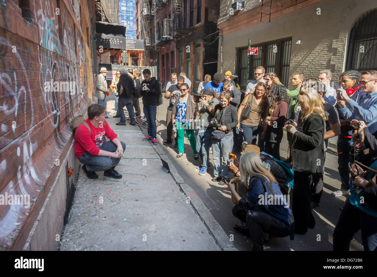 New York, USA. 15 octobre 2013. Les amateurs de street art affluent au quartier de Tribeca de New York le mardi, Octobre 15, 2013 à voir la quinzième tranche de graffiti de Banksy, l'art, 'Tribecca'. L'insaisissable artiste de rue, c'est la création d'œuvres autour de la ville chaque jour pendant le mois d'octobre et cette tranche montre une silhouette du World Trade Center avec une fleur en annexe. Crédit : Richard Levine/Alamy Live News Banque D'Images