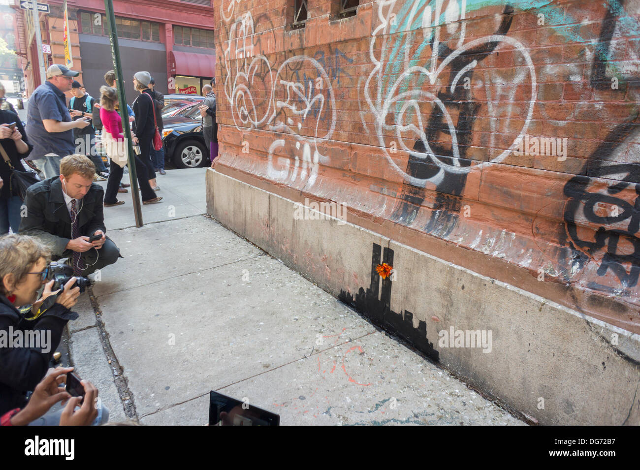 New York, USA. 15 octobre 2013. Les amateurs de street art affluent au quartier de Tribeca de New York le mardi, Octobre 15, 2013 à voir la quinzième tranche de graffiti de Banksy, l'art, 'Tribecca'. L'insaisissable artiste de rue, c'est la création d'œuvres autour de la ville chaque jour pendant le mois d'octobre et cette tranche montre une silhouette du World Trade Center avec une fleur en annexe. Crédit : Richard Levine/Alamy Live News Banque D'Images