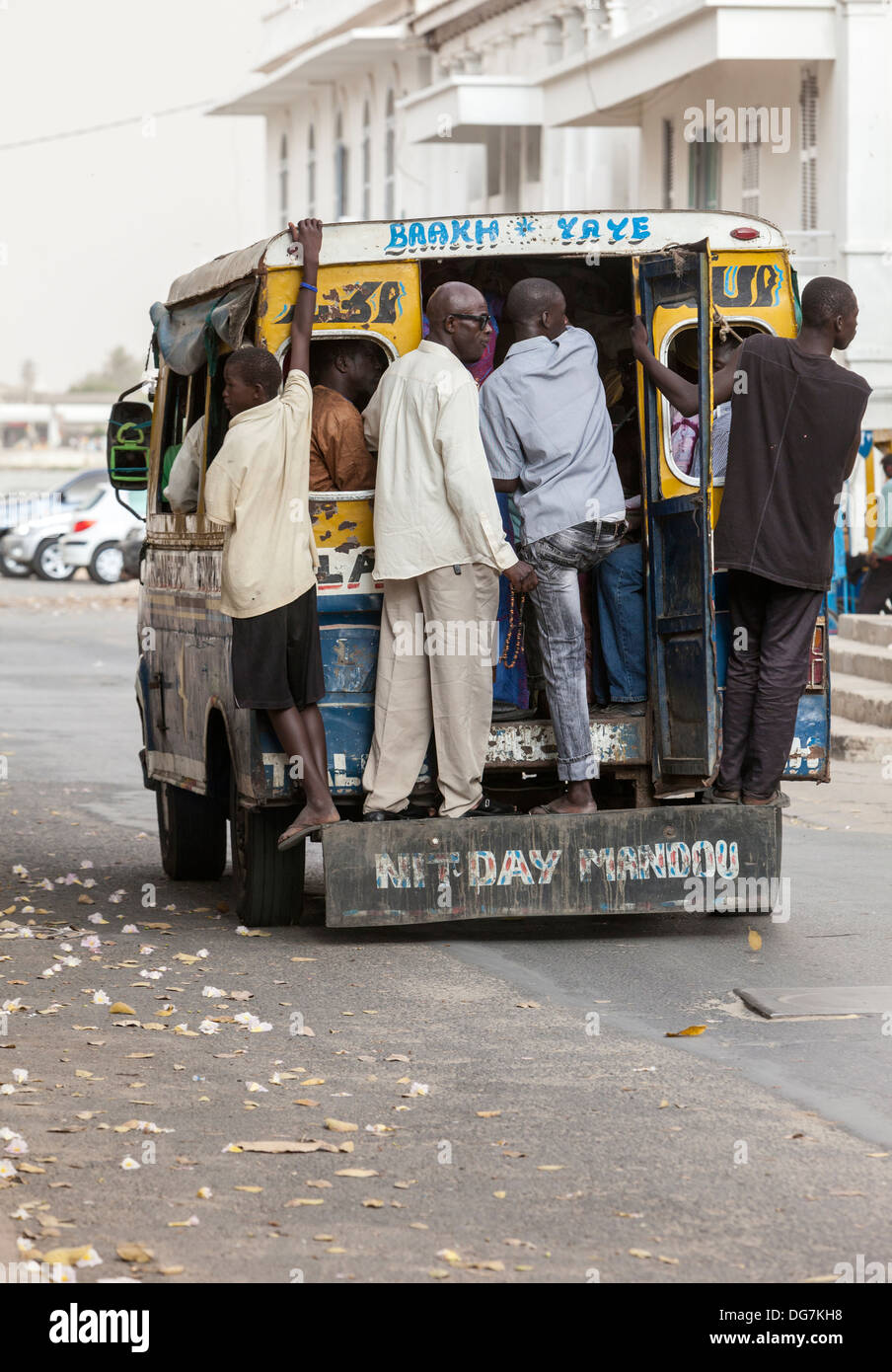 Sénégal, Saint Louis. Les hommes s'accrocher à l'arrière d'un minibus. Banque D'Images