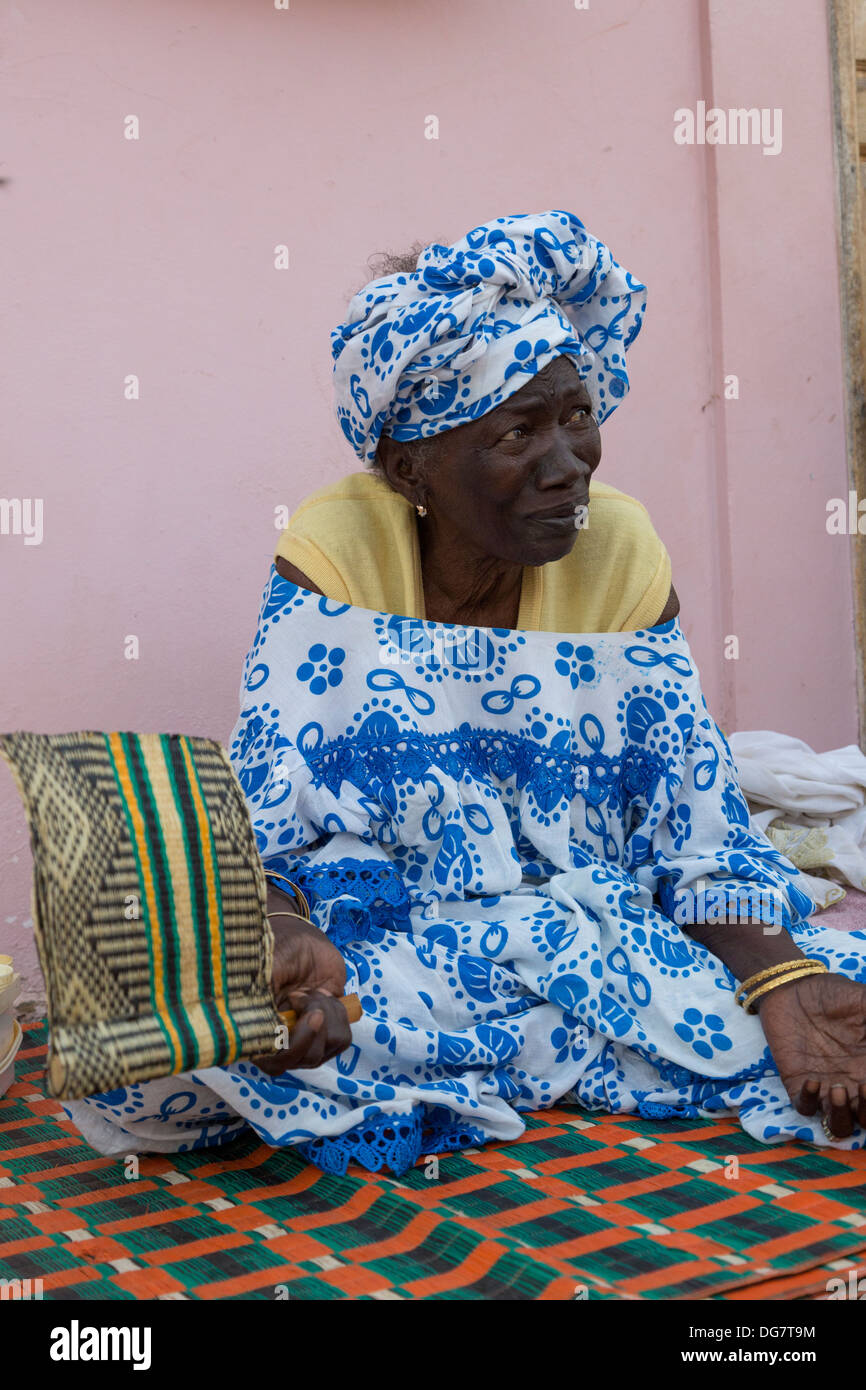 Sénégal, Saint Louis. Vieille Femme Sénégalaise avec ventilateur assise sur son porche. Banque D'Images