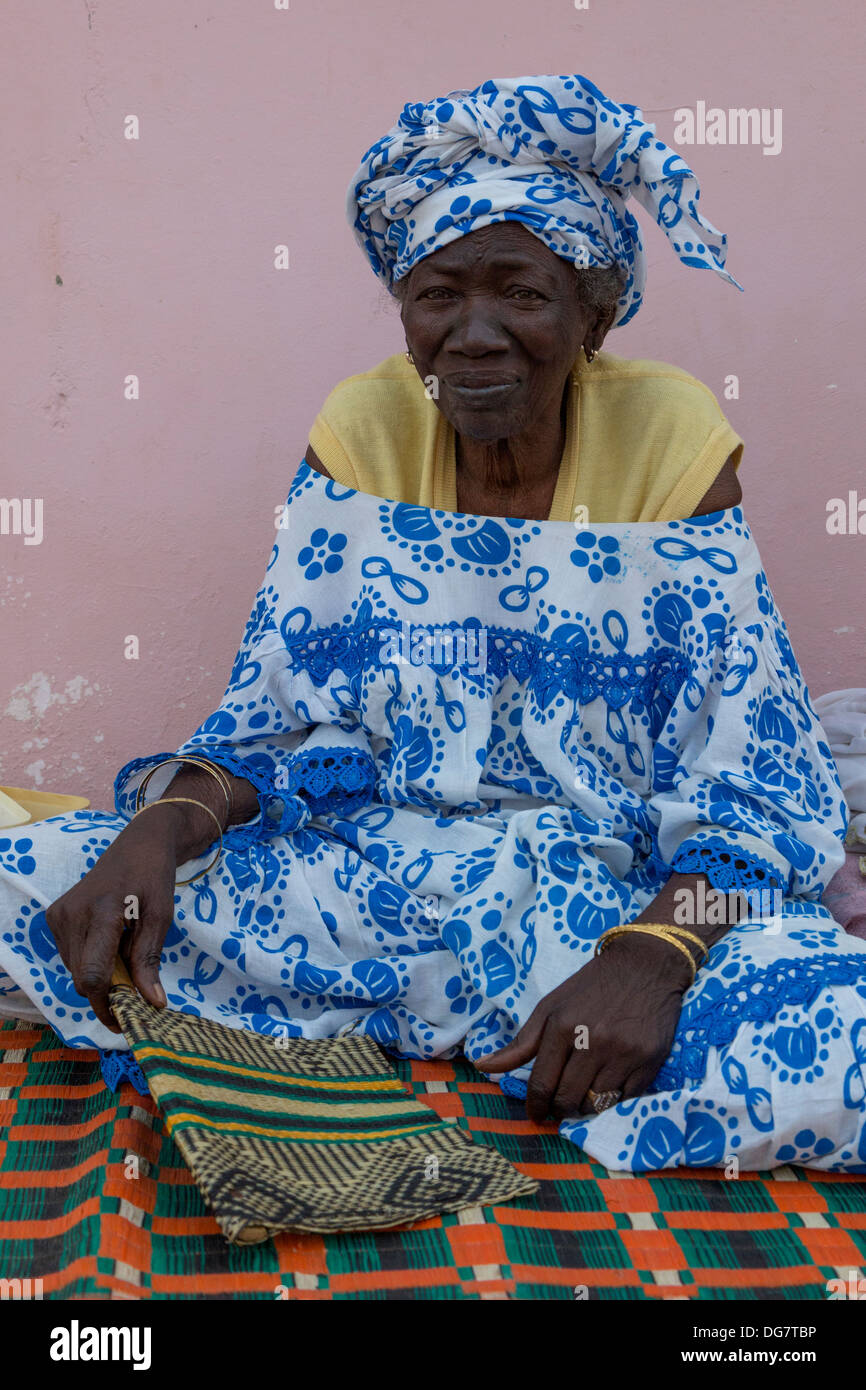 Sénégal, Saint Louis. Vieille Femme Sénégalaise avec ventilateur assise sur son porche. Banque D'Images