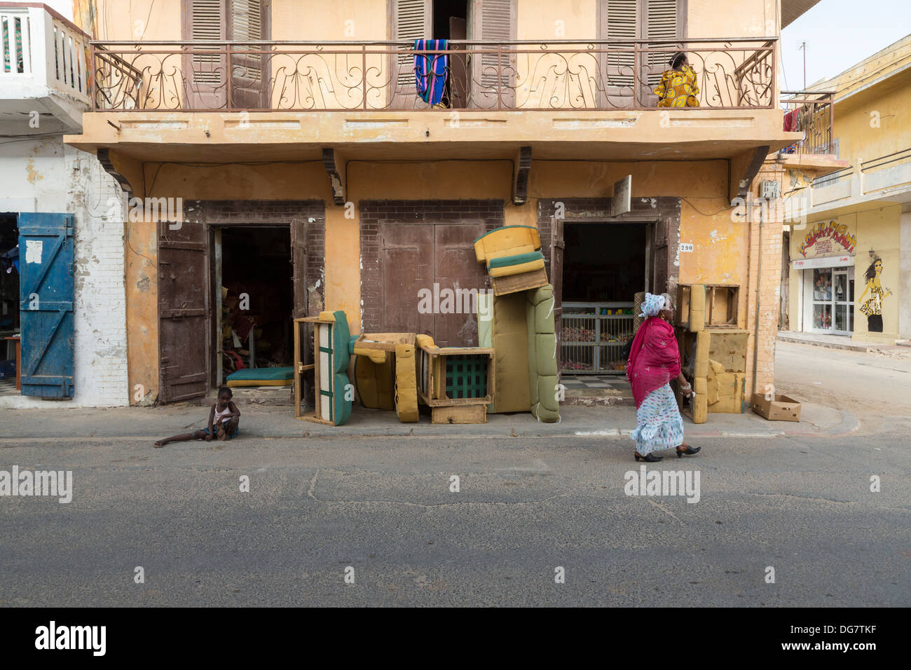 Sénégal, Saint Louis. Femme marche passé atelier de rembourrage de meubles. Banque D'Images