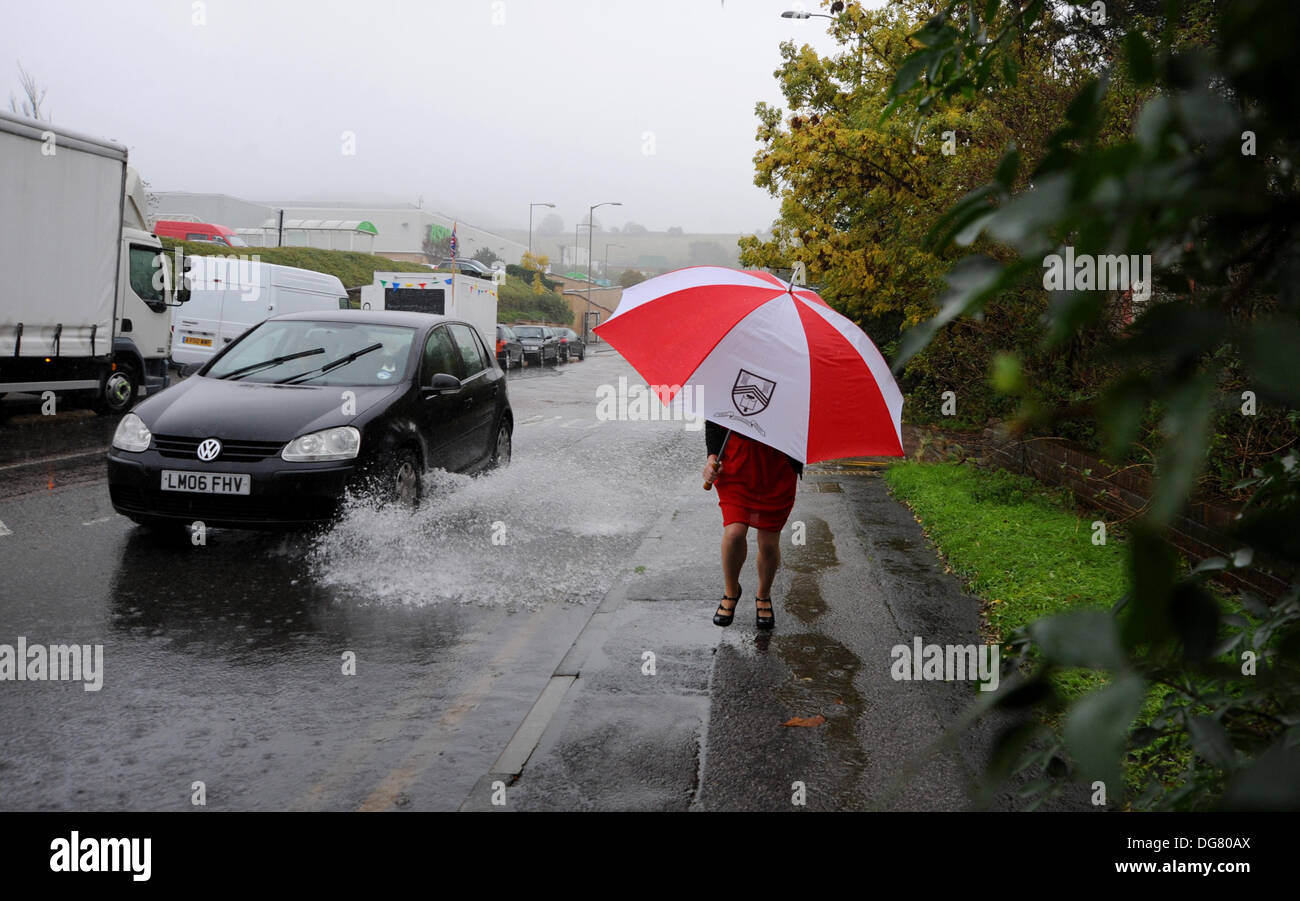 Une femme avec un parapluie passe devant l'eau d'inondation sur une route de Brighton que heavy rain cause des problèmes dans le Sussex aujourd'hui Banque D'Images