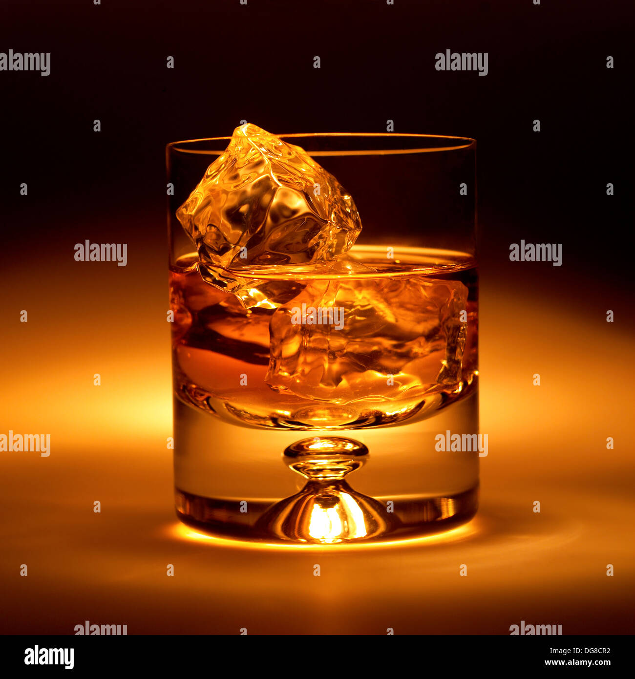 Old fashioned verre avec de la glace et du whisky sur un fond noir et or à moitié plein. Banque D'Images