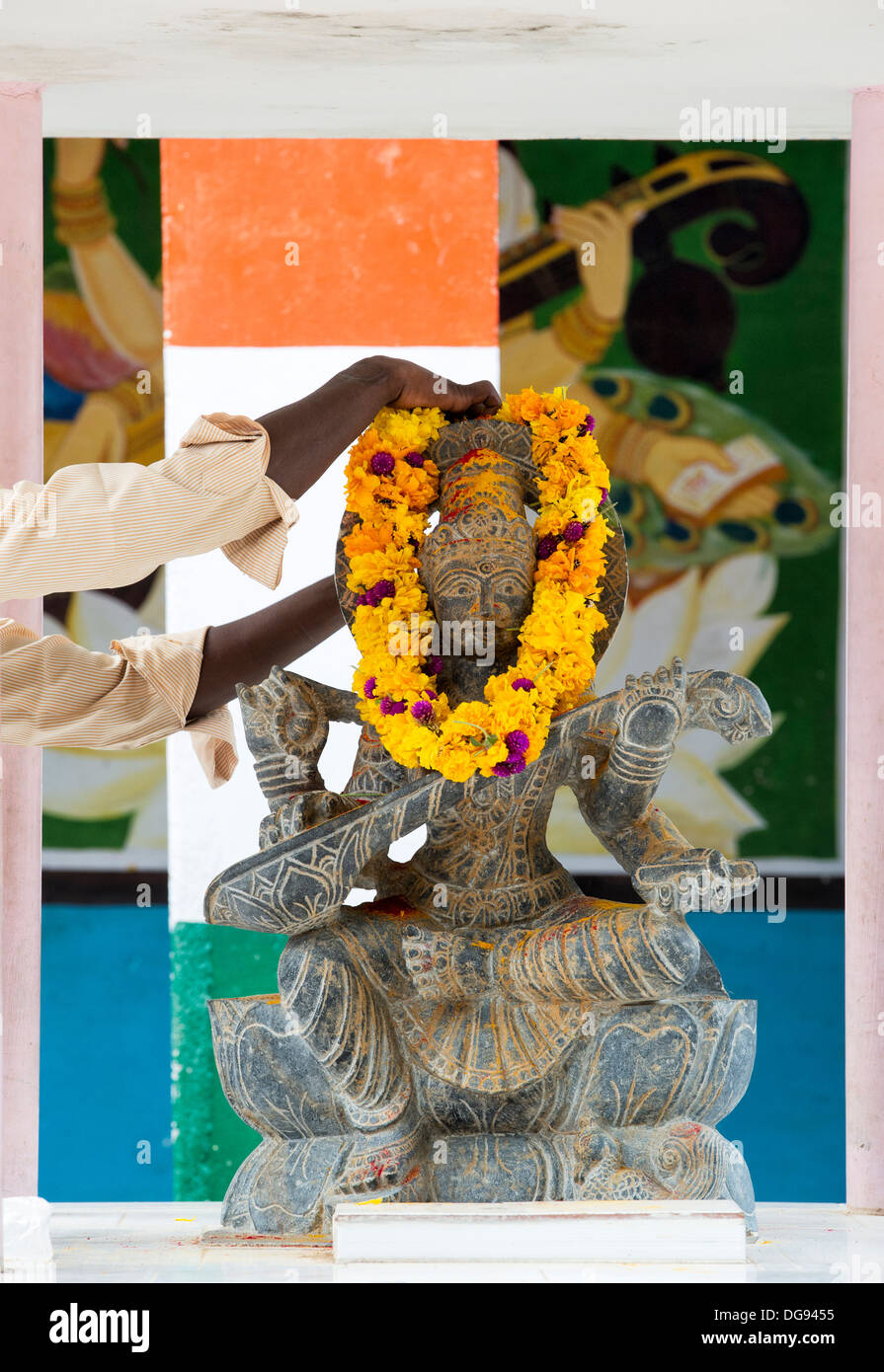 Indian man putting flower garland sur divinité hindoue Sarawathi statue. L'Andhra Pradesh, Inde Banque D'Images