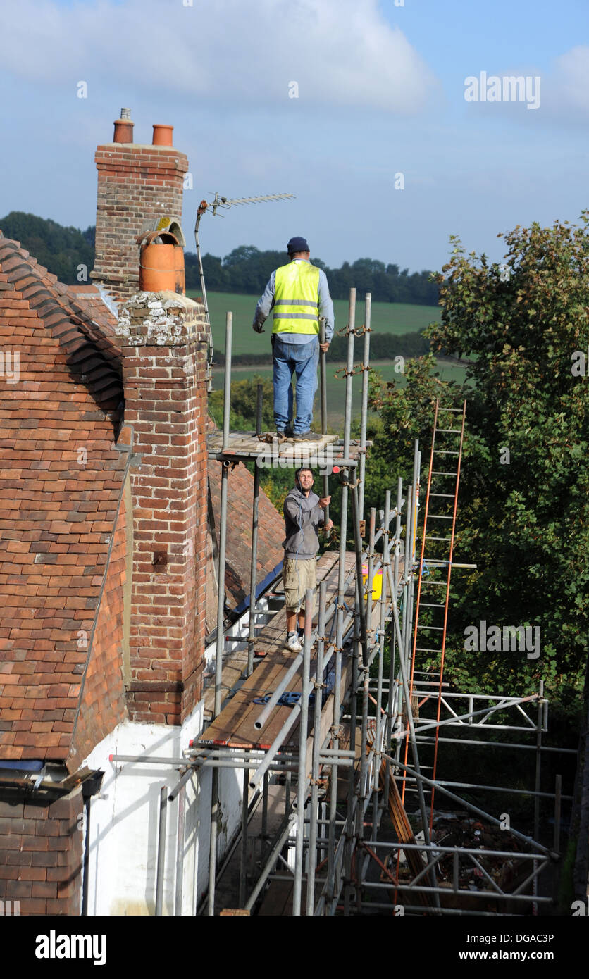 Les constructeurs travaillent sur des échafaudages la réparation de toiture sur vieille maison au combat High Street Sussex UK Banque D'Images