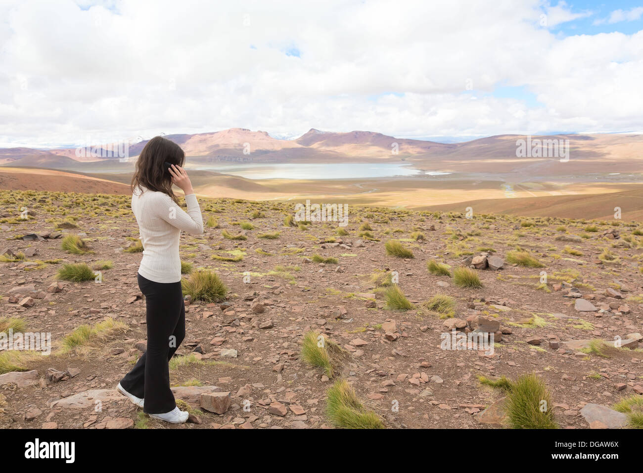 Woman talking on mobile phone et enjoing panorama de l'altiplano bolivien avec lagoon Morejon, Bolivie Banque D'Images