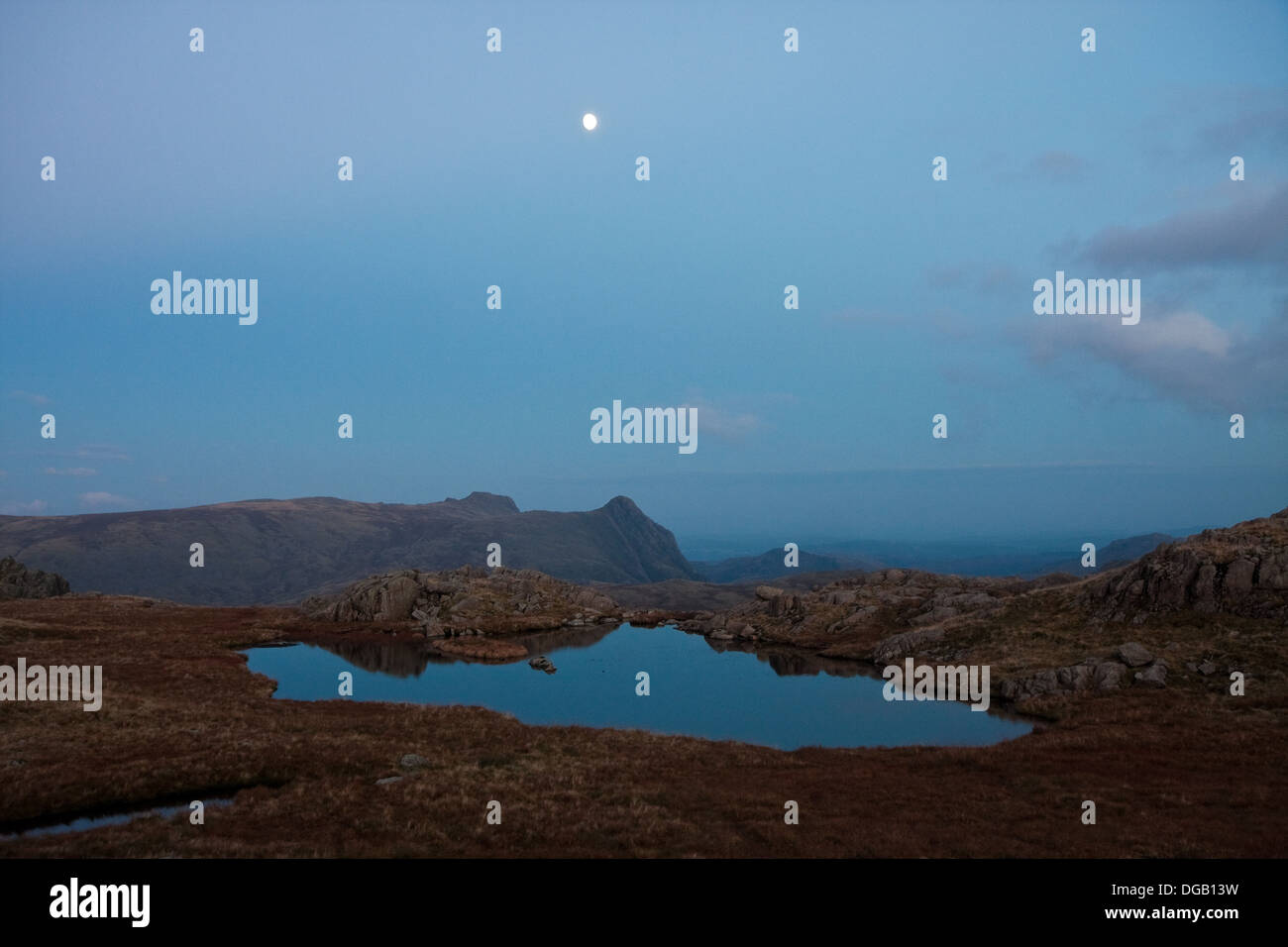 La lune se lève sur les Langdale Pikes, Haarrison Stickle, gauche, et le brochet de Stickle, dans le Lake District comme dusk falls Banque D'Images