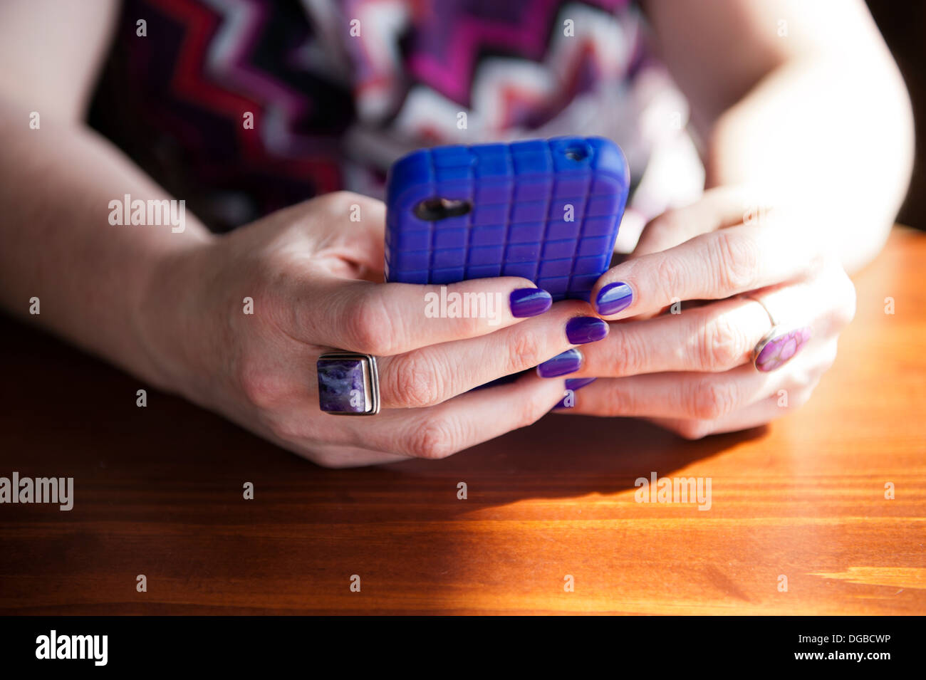 Dame tenant un téléphone intelligent avec un cas de pourpre et des ongles des doigts. Banque D'Images