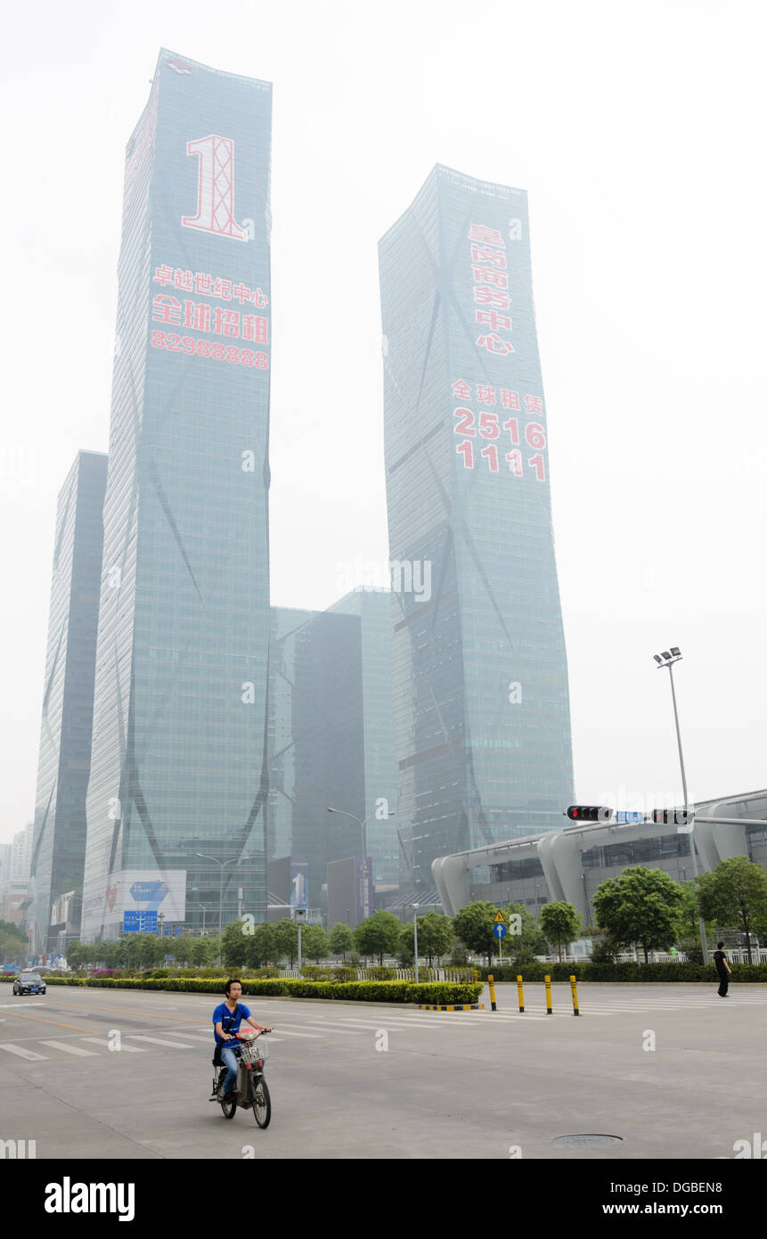 D'immenses gratte-ciel flambant neuf pour location en Chine ; à l'avant-plan des promenades d'une personne une moto électrique à travers la brume Banque D'Images