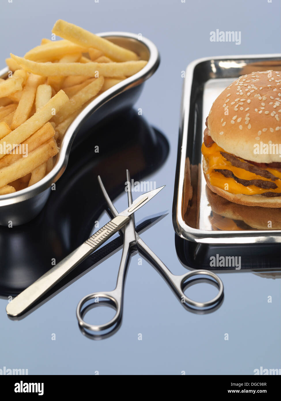 Burger et frites assis dans des plateaux chirurgicaux illustrant une mauvaise alimentation Banque D'Images