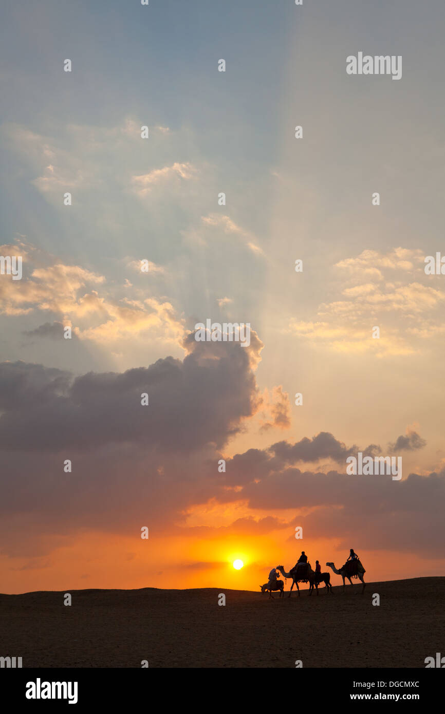 Un groupe de personnes hors de la tête vers le soleil couchant sur les chameaux et les ânes Banque D'Images