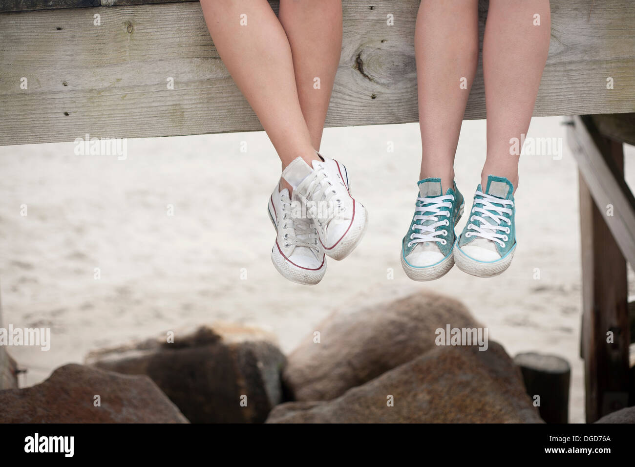 Young women sitting on pier, sur la plage, low section Banque D'Images