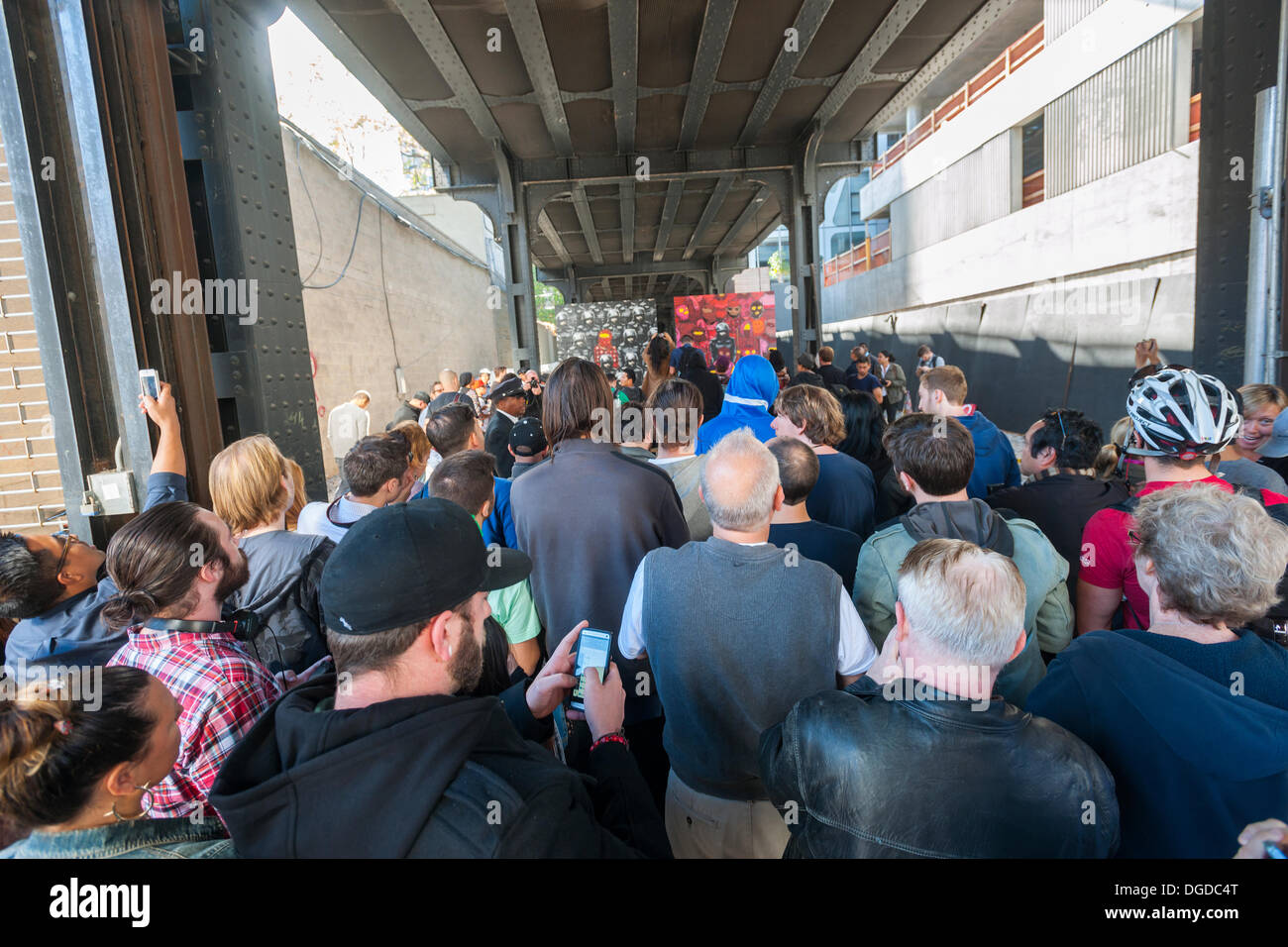 New York, USA. 18 octobre 2013. Les amateurs d'art de rue à la mode troupeau Chelsea West district Gallery à New York pour voir la dix-huitième tranche de l'art graffiti de Banksy, une collaboration avec les artistes brésiliens, Os Gemeos. Cette tranche est configuré comme une exposition de musée dans un lot vide sous le parc High Line complet avec le "musée" des gardes pour gérer le contrôle des foules. L'insaisissable artiste de rue, c'est la création d'œuvres autour de la ville chaque jour pendant le mois d'octobre. Crédit : Richard Levine/Alamy Live News Banque D'Images