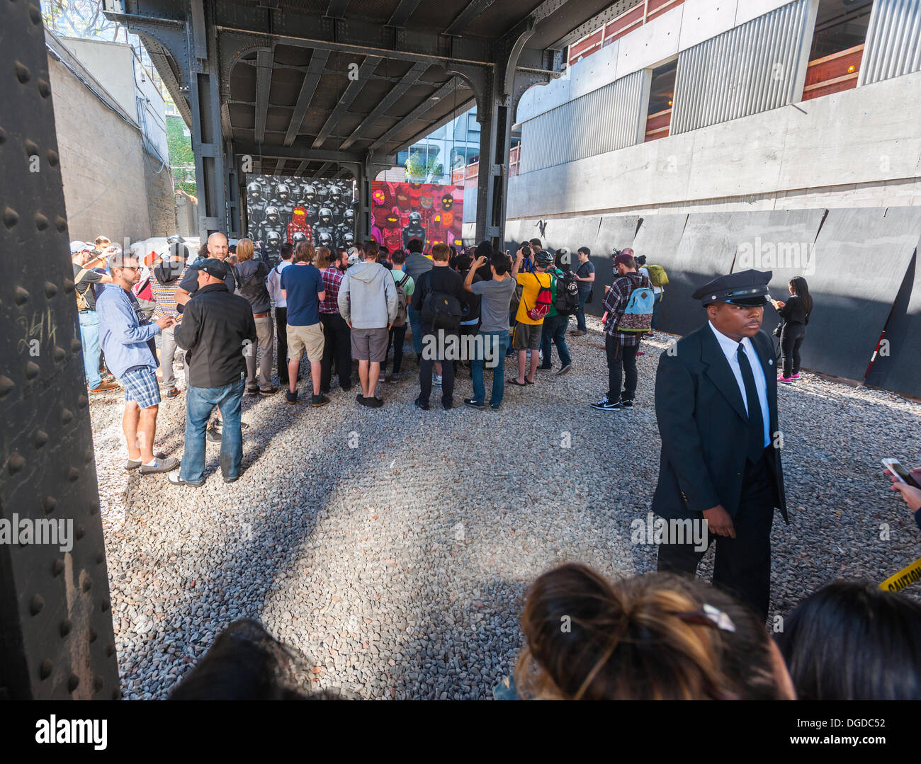 New York, USA. 18 octobre 2013. Les amateurs d'art de rue à la mode troupeau Chelsea West district Gallery à New York pour voir la dix-huitième tranche de l'art graffiti de Banksy, une collaboration avec les artistes brésiliens, Os Gemeos. Cette tranche est configuré comme une exposition de musée dans un lot vide sous le parc High Line complet avec le "musée" des gardes pour gérer le contrôle des foules. L'insaisissable artiste de rue, c'est la création d'œuvres autour de la ville chaque jour pendant le mois d'octobre. Crédit : Richard Levine/Alamy Live News Banque D'Images