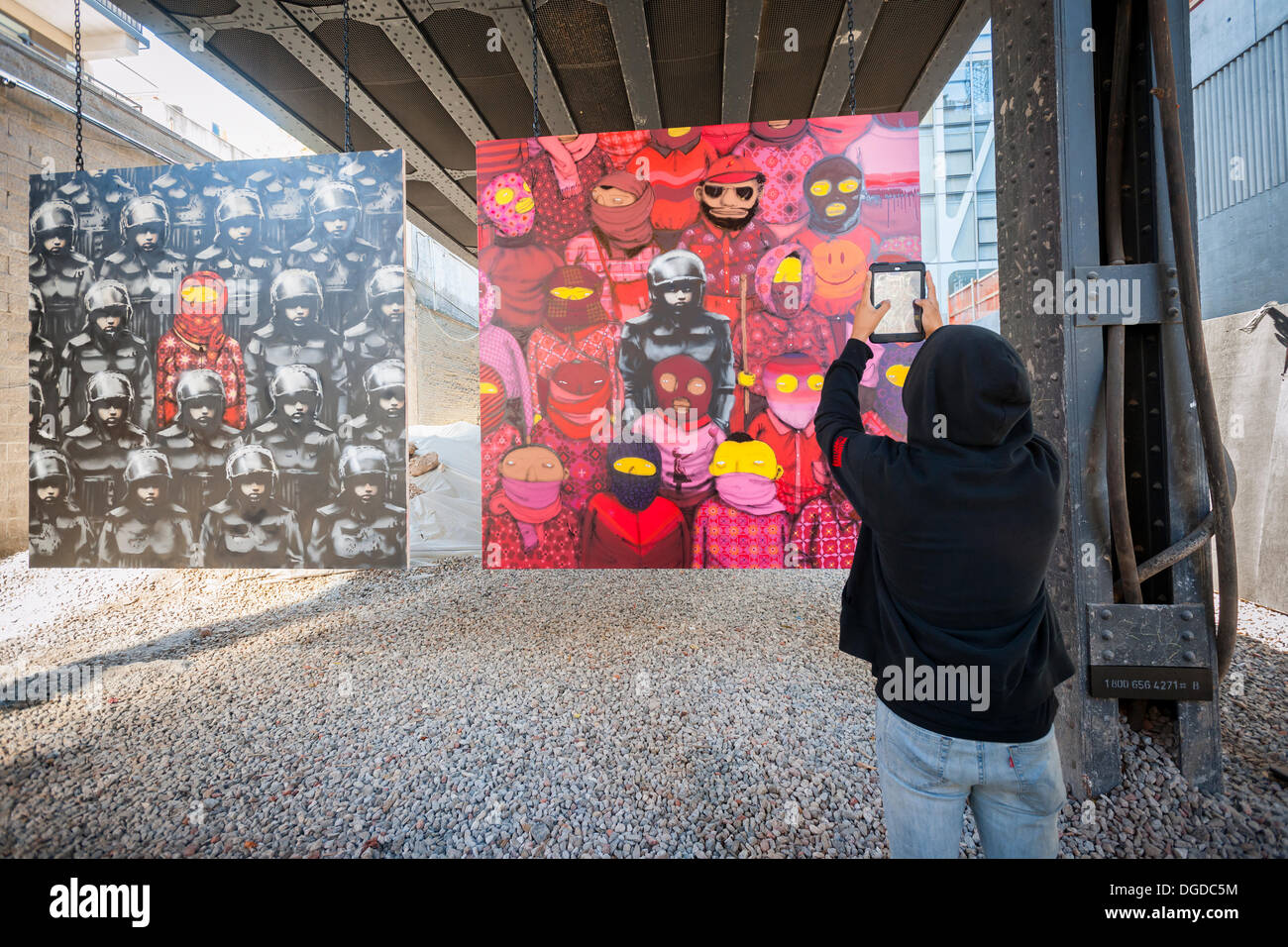 New York, USA. 18 octobre 2013. Les amateurs d'art de rue à la mode troupeau Chelsea West district Gallery à New York pour voir la dix-huitième tranche de l'art graffiti de Banksy, une collaboration avec les artistes brésiliens, Os Gemeos. Cette tranche est configuré comme une exposition de musée dans un lot vide sous le parc High Line complet avec le "musée" des gardes pour gérer le contrôle des foules. L'insaisissable artiste de rue, c'est la création d'œuvres autour de la ville chaque jour pendant le mois d'octobre. Crédit : Richard Levine/Alamy Live News Banque D'Images