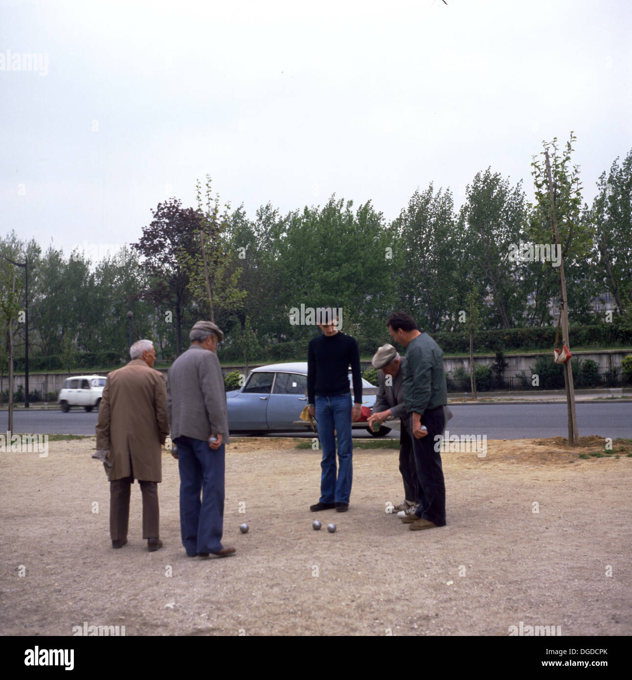 Photo des années 1960 montrant un groupe d'hommes jouant aux boules sur une cour de gravier à côté d'une route, Paris, France. Banque D'Images