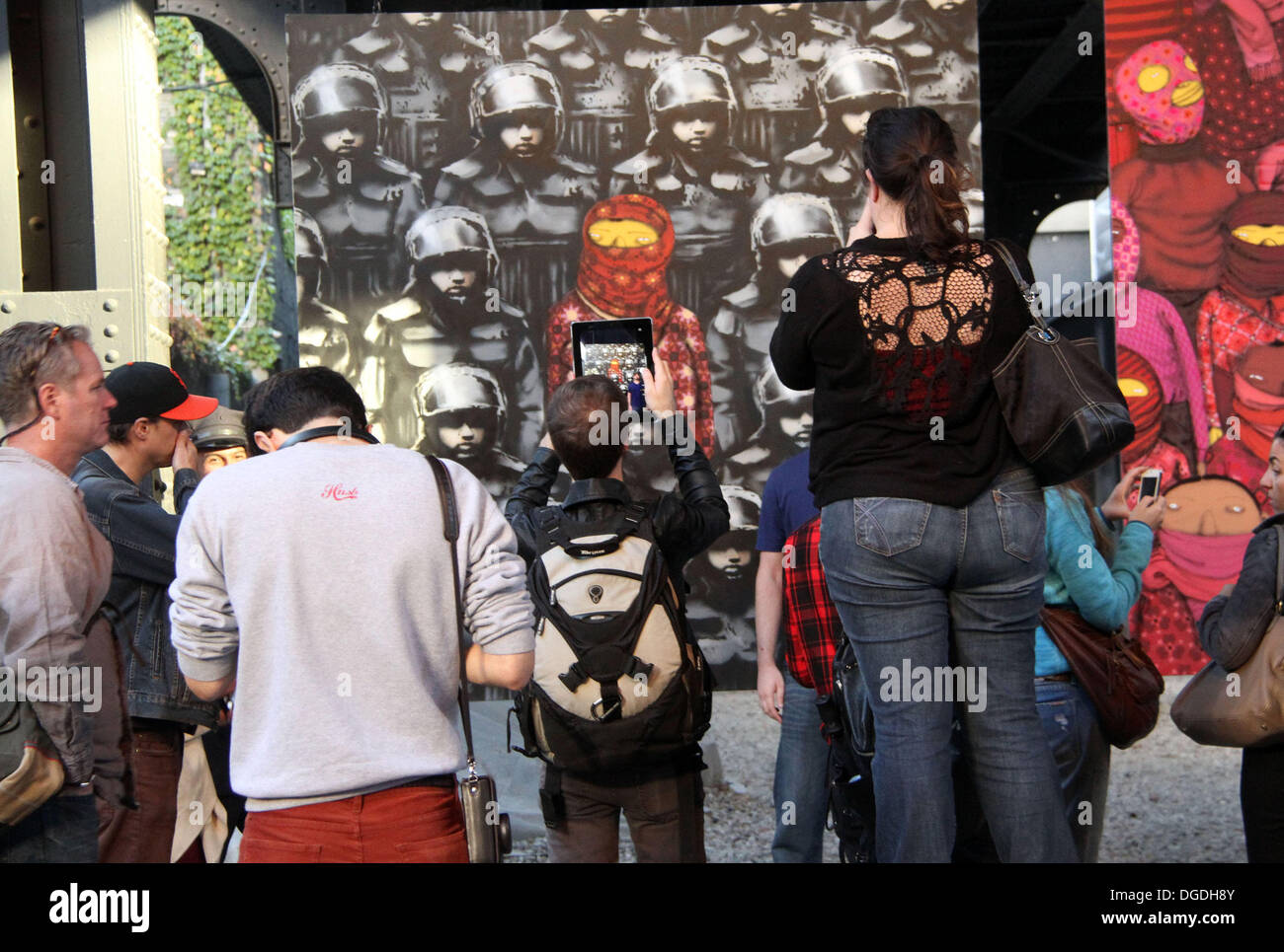 New York, USA. 18 Oct, 2013. L'artiste graffiti BANKSY, connu pour son style pochoir, collabore avec les frères jumeaux identiques brésiliens OS GEMEOS, connus pour leur caricature teintée de jaune pour le "mieux que dans l' art de rue ont lieu sur Paris. Les pièces situé dans l'ouest de Chelsea le 24 St entre la 10e et 11e st. Les peintures sont suspendus à un chevalet de fer & gardé pour empêcher de dégradation. Credit : Nancy Kaszerman ZUMAPRESS.com/Alamy/Live News Banque D'Images