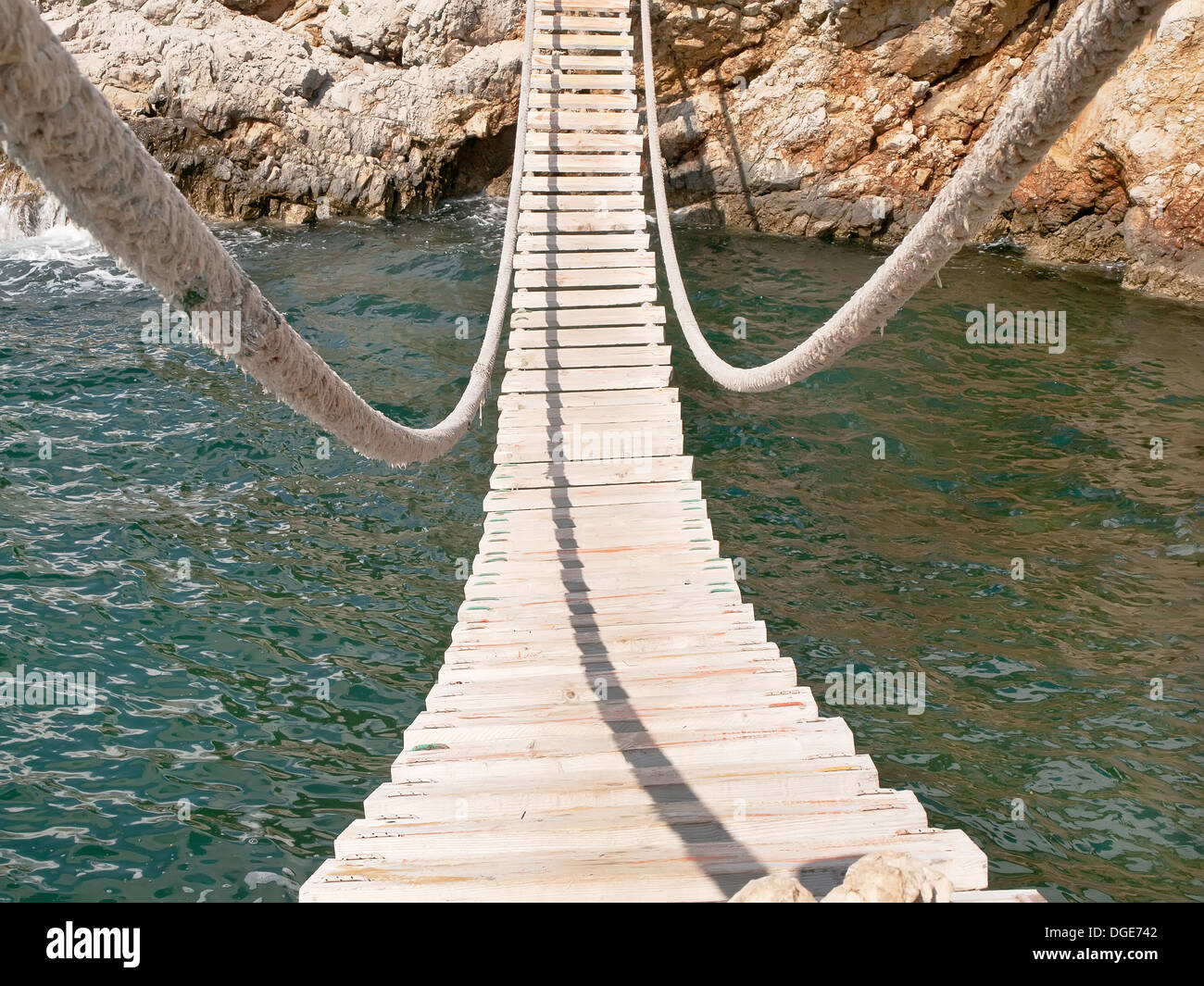 Hanging wooden bridge connect rocky mer-coûts Banque D'Images