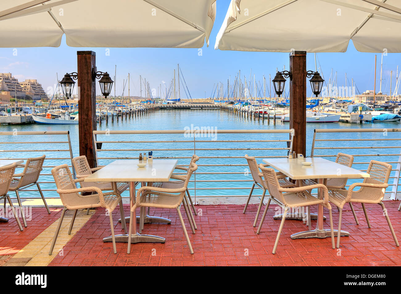 Des tables et des chaises blanches de restaurant en plein air sur la promenade le long de marina sur la mer Méditerranée à Ashkelon, en Israël. Banque D'Images