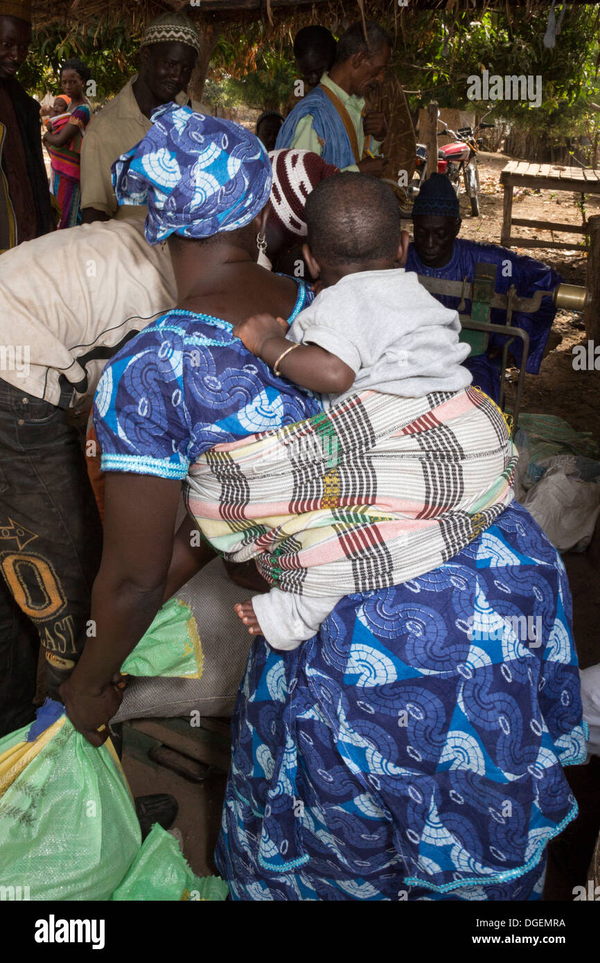 Marché hebdomadaire à Fass Njaga Choi, North Bank Region, la Gambie. Femme transportant bébé sur le dos. Banque D'Images