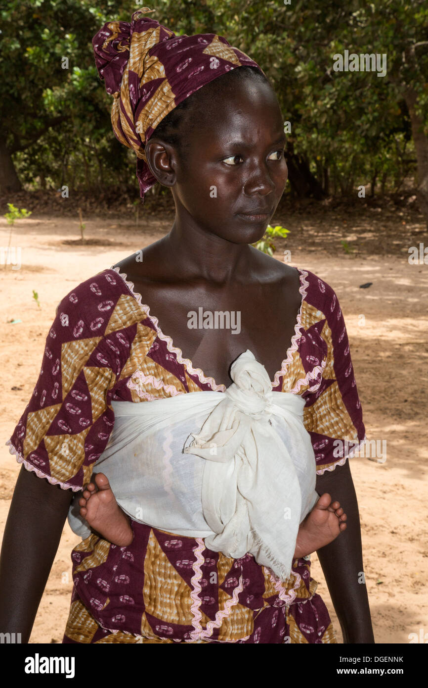 Jeune femme gambienne Carrying Baby sur le dos. Remarque Les pieds de chaque côté de la taille. Fass Njaga Choi, North Bank Region, la Gambie. Banque D'Images