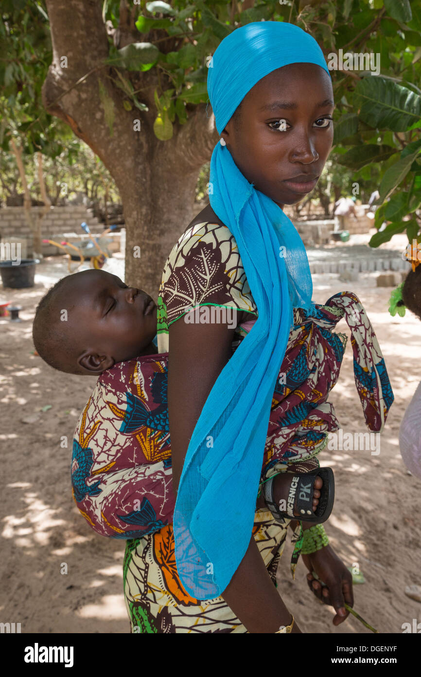 Jeune mère portant gambien, fils de couchage sur le dos, Fass Njaga Choi, North Bank Region, la Gambie. Banque D'Images