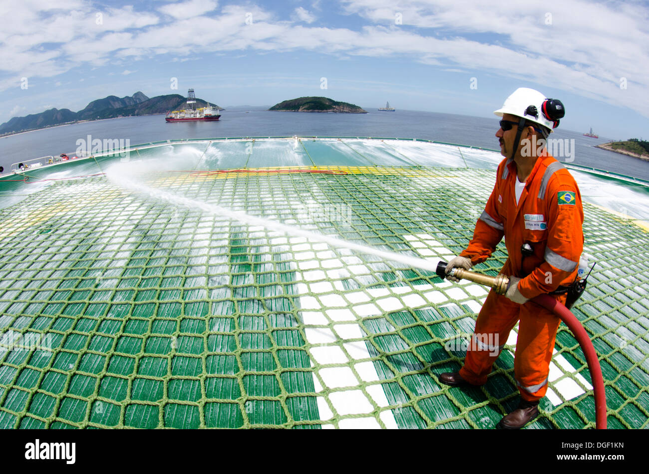 Les membres d'équipe de forage d'huile contrôle de la ligne de canons à mousse pont d'atterrissage de l'hélicoptère à l'OCEAN RIG MYKONOS navire de forage. Banque D'Images