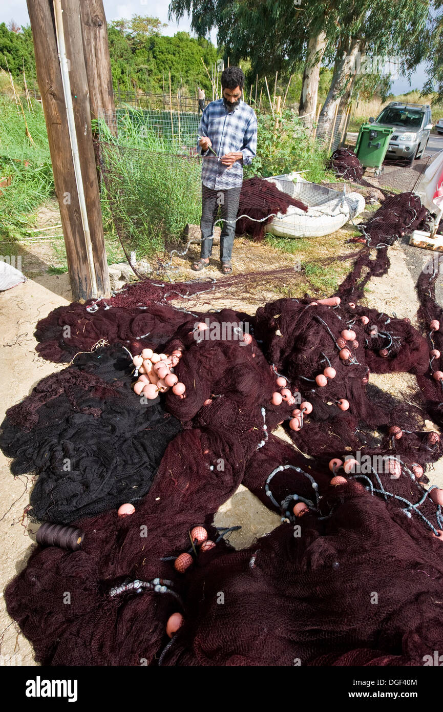 Un pêcheur réparant ses filets de pêche près d'un village appelé Roda sur la côte nord de Corfou en Grèce. Banque D'Images