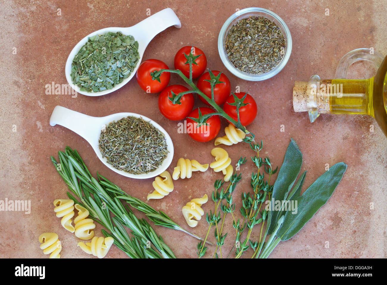 Les herbes, les tomates cerise et d'huile d'olive sur la surface de terre cuite Banque D'Images