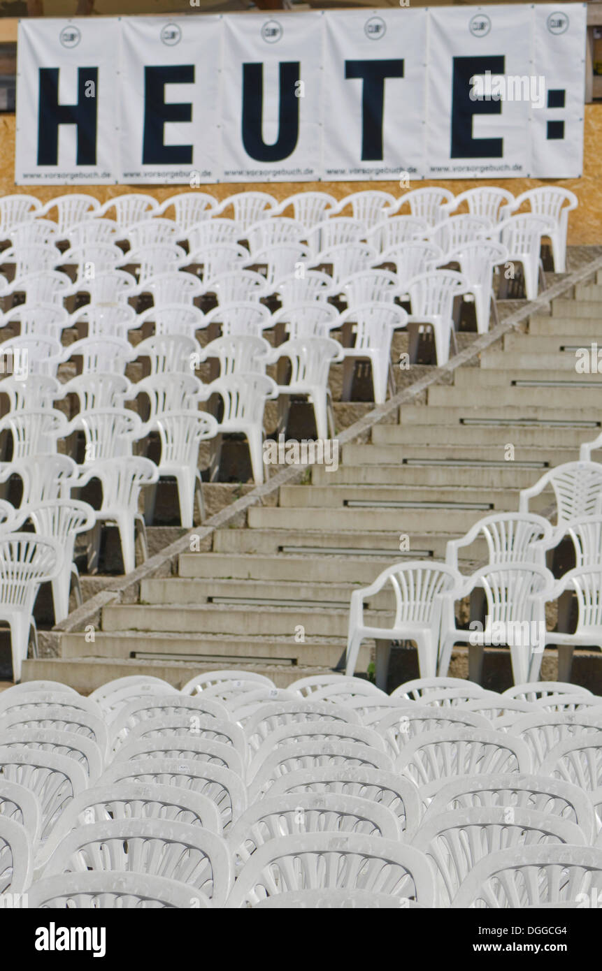 Panneau "heute", l'allemand pour "aujourd'hui", et des chaises en plastique blanc disposés en rangées à un concert en plein air, Dresden Banque D'Images